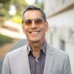 A photo of Sergio Garcia. He is wearing a gray suit jacket and sunglasses and smiling.