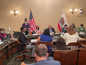 In the Assembly HiEd Hearing Room testifying table from left to right, Chidi Agu, CCCCO Dr. Aisha Lowe, and Assemblymember Irwin
